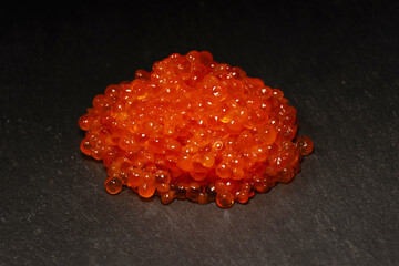 Red trout caviar on a black background.