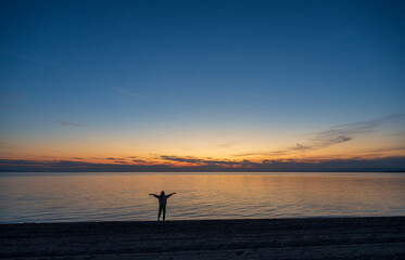 A teenage girl is meditating and exercising on the seashore watching a beautiful sunset. Sithonia, Greece, Halkidiki. Paradisos Beach in Neos Marmaras.

