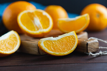 Sliced oranges fruit near denim textile on wooden board. Orange juicy fruit, citrus minimal concept