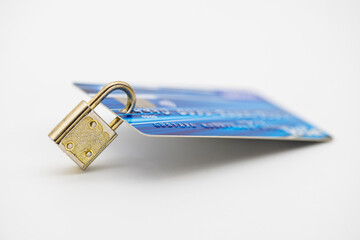 Tarjeta de crédito de un banco protegida por un candado metálico, aislado en blanco  - obrazy, fototapety, plakaty