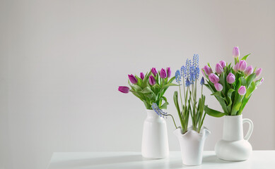 spring flowers in white vases in white interior