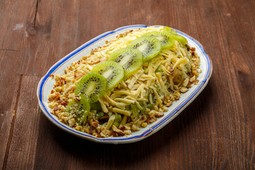 Chicken salad decorated with kiwi and nuts and Thai chicken on a plate on a wooden table