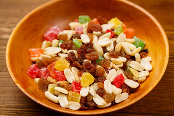 Scattered mix of dried fruits and nuts on a wooden plate.
