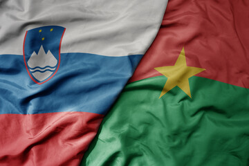 big waving national colorful flag of burkina faso and national flag of slovenia.