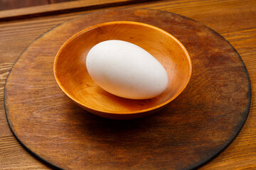 goose egg in a wooden plate on the table. Horizontal