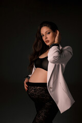 beautiful pregnant woman with dark hair in elegant clothes posing in studio - 750909201