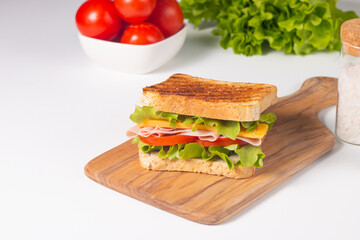 Close-up of two sandwiches with bacon, salami, prosciutto and fresh vegetables on rustic wooden cutting board. Club sandwich concept - 750911238