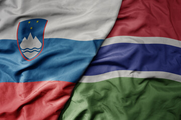 big waving national colorful flag of gambia and national flag of slovenia.