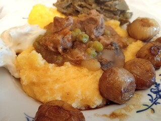 typical northern Italian dish with meat stew, polenta, cheese, peas, artichokes and spring onions