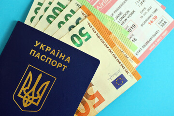 Ukrainian biometrical passport and european Euro money bills with Airlines avia tickets on blue background close up