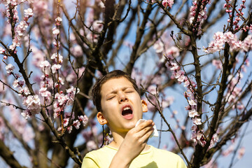 Child with pollen allergy. Boy sneezing and blowing nose because of seasonal allergy