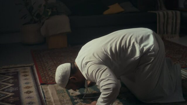 Side tilt footage of Biracial muslim man atoning for his sins during prayers to Allah in sajdah position at home