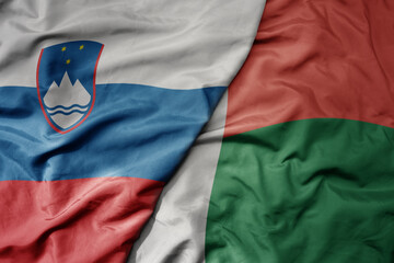 big waving national colorful flag of madagascar and national flag of slovenia.