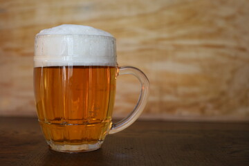 large pint of beer with foam in  wooden background