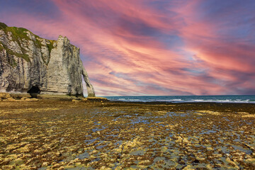 Famous cliff Aval of Etretat at low tide, at sunset. Etretat is a commune in the Seine-Maritime department in the Haute-Normandie region in northwestern France, famous French seaside resort.