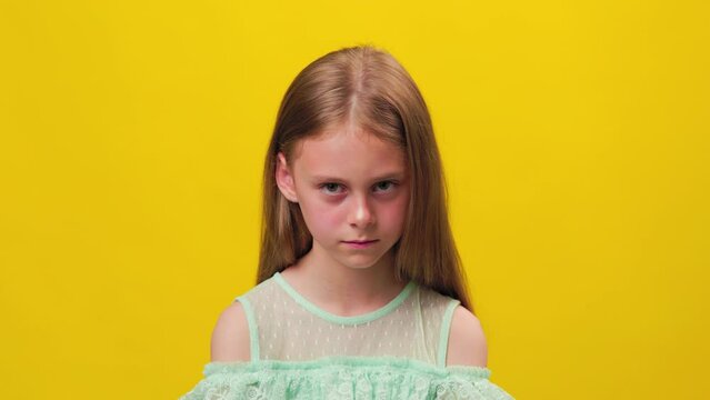 sad preteen girl kid looking at camera on yellow background