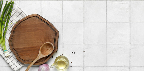 Wooden board with oil, garlic and onion on white tile kitchen table