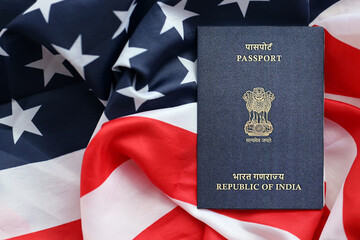 Blue Indian passport on United States national flag background close up. Tourism and diplomacy...