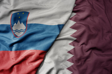 big waving national colorful flag of qatar and national flag of slovenia.