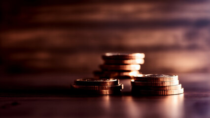 Elegant dark wood table with stacks of coins in concept of economy, savings and investment.