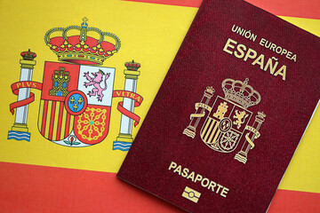 Red Spanish passport of European Union on national flag background close up. Tourism and...
