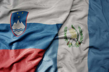 big waving national colorful flag of guatemala and national flag of slovenia.