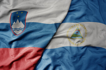 big waving national colorful flag of nicaragua and national flag of slovenia.