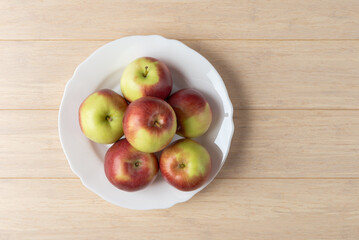 Fresh apples on a plate over wooden table - 750933088