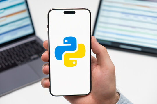 PRAGUE, CZECH REPUBLIC - JANUARY 21 2024: Python logo on the screen of smartphone in mans hand on the workplace background. 