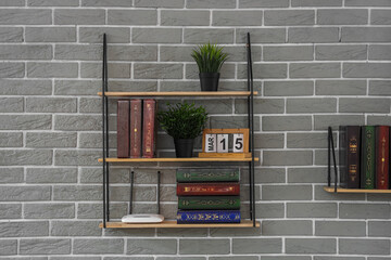 Bookshelf with modern wi-fi router and plants on grey brick wall