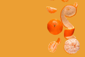 Flying sweet ripe mandarins on yellow background