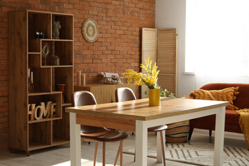 Stylish interior of loft style living room with table, vase of flowers, chairs and shelving unit