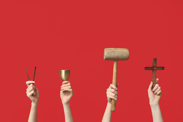 Female hands with wooden cross, mallet, cup and nails on red background. Good Friday concept