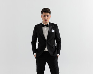 sexy fashion man wearing black suit holding pockets