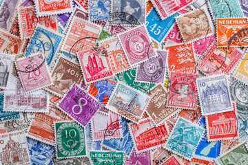 Ukraine, Kiyiv - January 12, 2023.Postage stamps.Collection of stamps and magnifying glass.A collection of world stamps in a pile.Postage stamps from different countries and times - obrazy, fototapety, plakaty