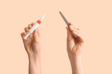 Female hands with cuticle oil pen and nail file on beige background