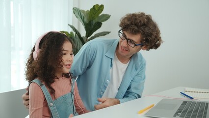 Caucasian dad put headphones on daughter while girl learning code. Father take care schoolgirl...