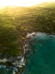 Aerial sunrise.Dark turquoise water with white foamy waves and green rocky shore