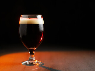 glass of dark beer on a black background . Copy space