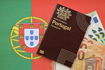 Red Portugal passport of European Union and money on flag background close up. Tourism and...