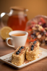 A cozy tea time scene with lemon, honey, cake, and blueberries on a wooden table