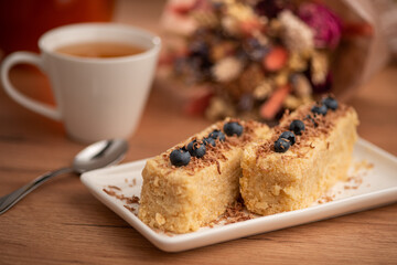 A cozy tea time scene with lemon, honey, cake, and blueberries on a wooden table