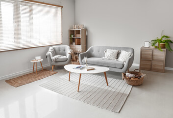 Interior of modern living room with grey sofa, armchair and table near window