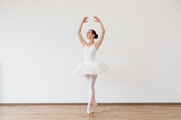 Beautiful young female ballet dancer bending over effortless on stage with harmony, body shape...