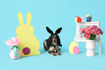 Cute cocker spaniel in bunny ears with Easter cake, beautiful tulips paper eggs and rabbit on blue background