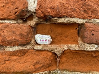 Old red brick with little, smaller stone in the crevice that says 'lichtpuntje'