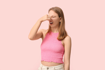 Young woman feeling terrible smell on pink background
