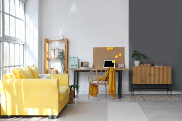 Interior of office with workplace, laptop, sofa and chest of drawers
