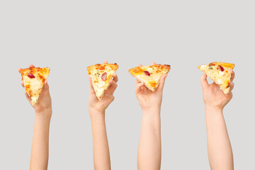 Many hands holding pizza slices on white background