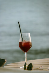 Elegant and relaxed scene, a table on which a glass of wine stands out. On side of the glass lies a pair of sunglasses. A cell phone appears. The sea in the background  Marbella, Spain